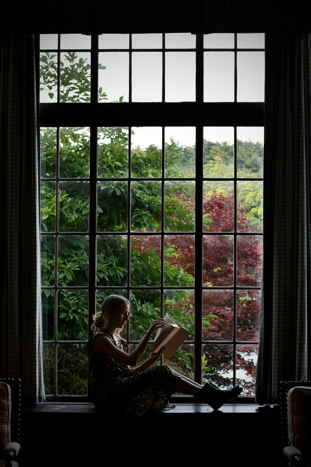 woman reading book by window